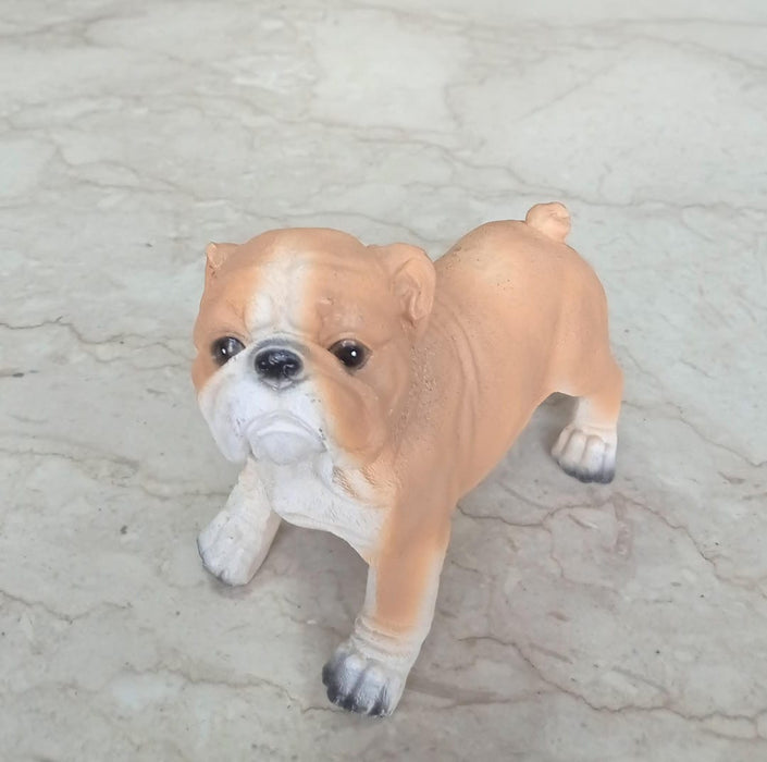 A small, realistic bulldog figurine in a fawn and white color, standing 