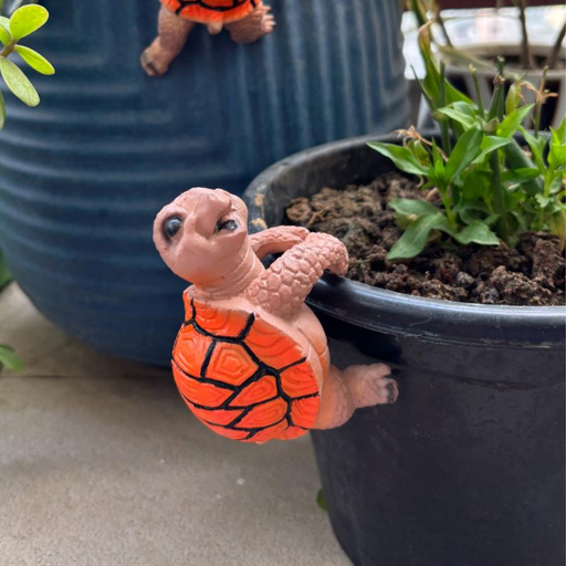 Orange shell tortoise pot hugger figurine designed to hang on the edge of a planter,