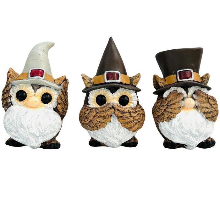 Three small owl statues with white beards and hats. One owl covers its ears, one covers its mouth, and one covers its eyes.