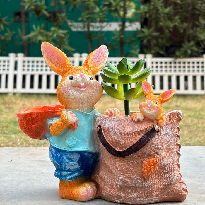 Orange rabbit figurine succulent planter featuring a large bunny carrying a sack with a baby bunny inside, placed next to green plants.