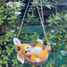 Cute yellow rabbit figurine sitting in a hanging basket swing