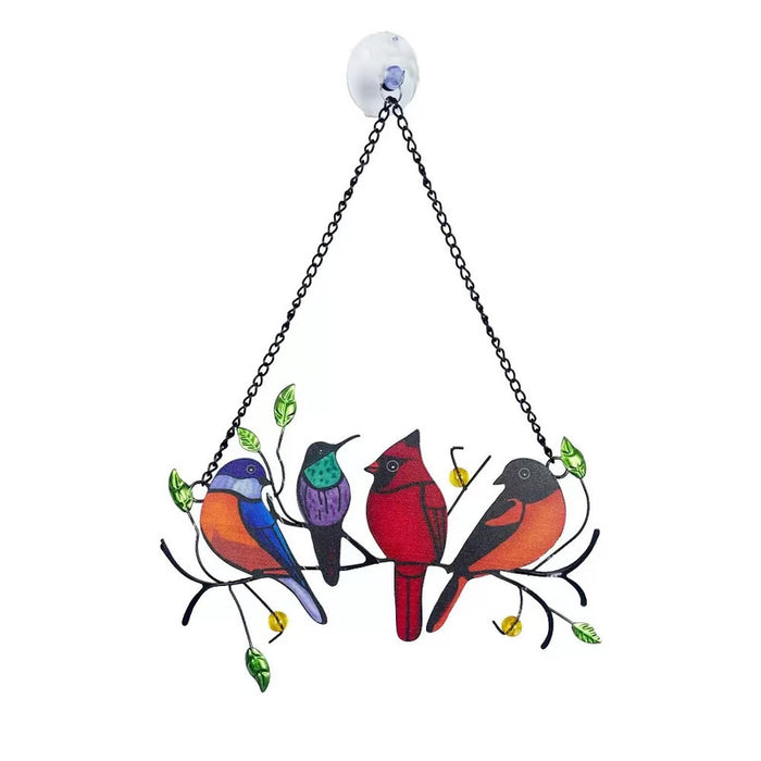 Colorful metal suncatcher with four songbirds (blue, purple, red cardinal, and orange/black bird) perched on a black metal branch with green leaves and yellow beads, hanging from a chain with a white suction cup.