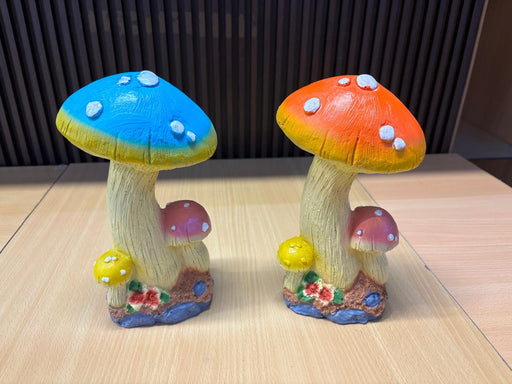 A pair of whimsical, hand-painted mushroom garden statues with vibrant blue and orange caps, featuring white spots, textured stalks, and smaller companion mushrooms at the base.