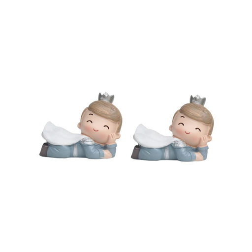 A pair of identical resin figurines of a small boy prince lying on his stomach, resting his chin on his hand. He wears a grey suit, a white cape, and a small silver crown on his head.