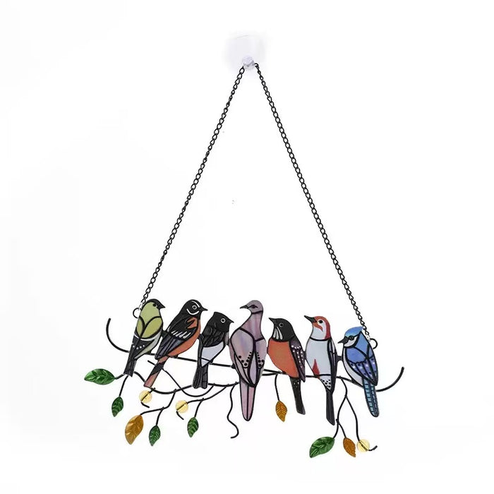 Hanging art piece featuring seven different colourful birds made from stained glass or acrylic, sitting on a black metal branch with green and gold leaves.