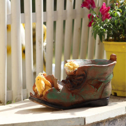 Rustic boot-shaped garden planter with yellow bunny accents, decorative weathered shoe flower pot for outdoor patio and garden decor.