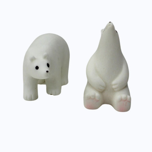 Assortment of small animal resin statues  placed on a mossy log in an outdoor setting.