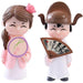Five pink pig figurines in various poses with gold ingots, a dollar coin, and a 100-dollar bill, symbolizing wealth and good fortune on a white background.