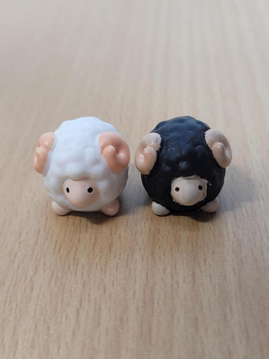 Pair of miniature black and white sheep figurines with curled horns, decorative resin ram statues for fairy gardens, terrariums, and desk decor.