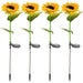 Four realistic artificial sunflower garden stakes with integrated solar panels and silver metal ground spikes, isolated on a white background.