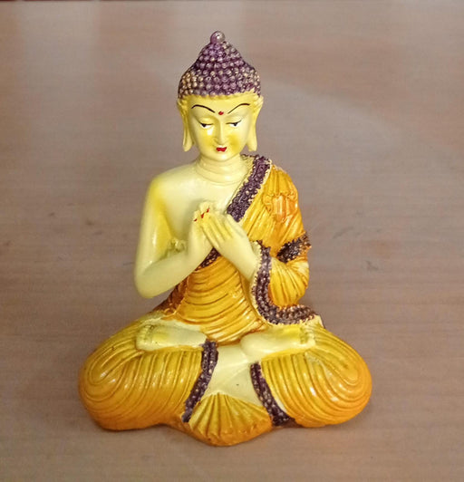 Detailed resin or polyresin Buddha figurine in yellow and purple, depicted in a prayer or greeting position.