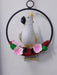 White cockatoo statue sitting on a red branch with pink flowers inside a black metal ring, decorative wall hanging.