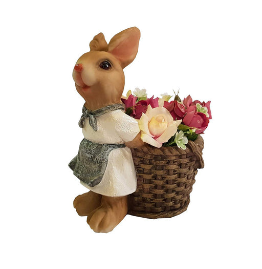 A miniature resin bunny gardener figurine wearing a white shirt and grey apron, carrying a woven basket filled with pink and cream roses, isolated on a white background.