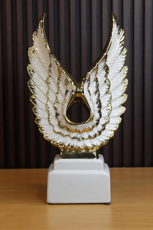 Modern white ceramic wing sculpture with gold-plated feather edges on a white pedestal, elegant luxury home decor and trophy-style centerpiece.