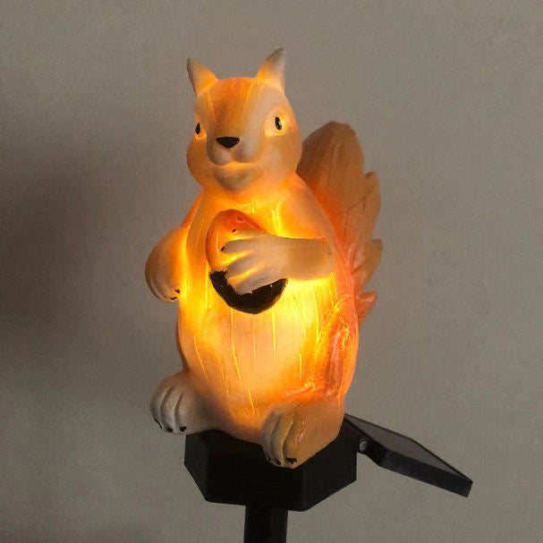 A side-by-side comparison of a resin squirrel solar garden stake light shown in daylight and illuminated with a warm amber glow at night.