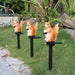 Solar-powered resin squirrel garden stake light glowing with warm orange light in the evening.