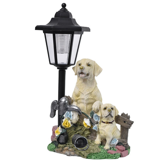 Yellow Golden Retriever dog and puppy garden statue standing next to a black solar-powered lamp post and a rustic fence with yellow flowers.