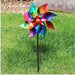 Colorful multicolor glitter garden windmill pinwheel decorative spinner on a black stake in green lawn