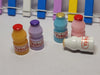 Group of colorful miniature probiotic drink bottles (Yakult style) with red, gold, and purple caps