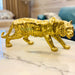 Golden tiger figurine with a metallic finish standing on a white marble table in a modern living room.