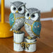 Intricately detailed resin owl figurine featuring two owls perched on white rustic pillars with teal and gold accents.