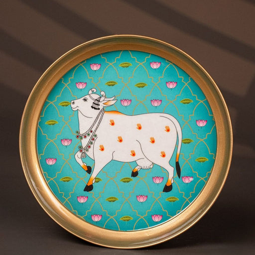 Gold-rimmed plate featuring a traditional Indian artwork of a bejeweled cow with handprints.