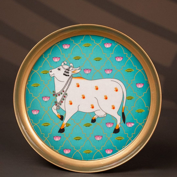 Gold-rimmed plate featuring a traditional Indian artwork of a bejeweled cow with handprints.