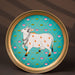 Gold-rimmed plate featuring a traditional Indian artwork of a bejeweled cow with handprints.