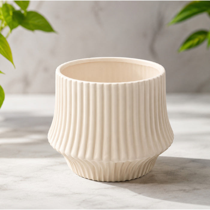 Cream ribbed ceramic planter pot placed on green artificial grass background