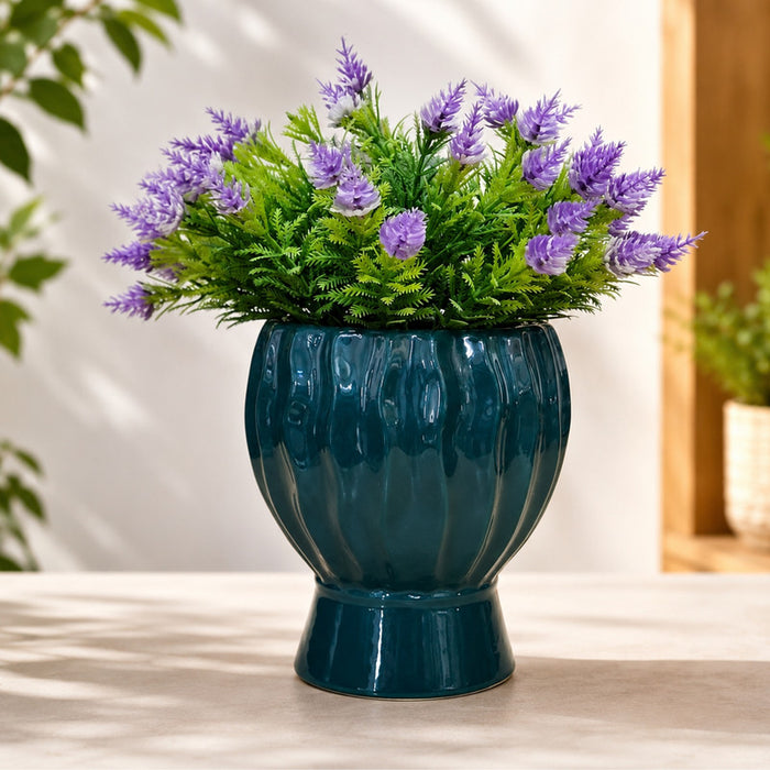 Teal ceramic ribbed planter pot with a pedestal base displayed on a wooden surface.