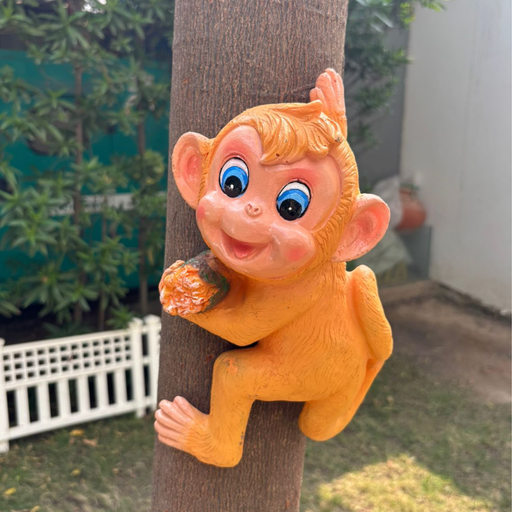 Vintage orange monkey "hugger" garden statue climbing a wooden post in a backyard setting.