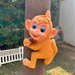 Vintage orange monkey "hugger" garden statue climbing a wooden post in a backyard setting.