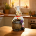 A whimsical kitchen figurine of a smiling chef with a mustache and white hat, leaning against a small wooden barrel used as a toothpick holder, displayed on a rustic wood stump.