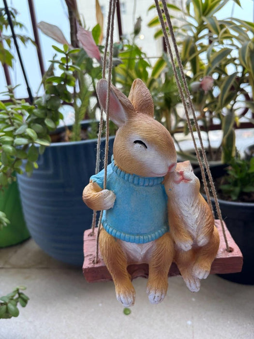 Hanging Mother & Baby small ceramic bunny figurines sitting on a miniature wooden swing,