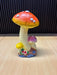 Hand-painted triple mushroom figurine with orange and pink caps, detailed gills, and a floral rocky base for garden decor.