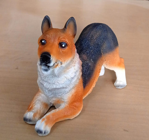 dog toy statue. The toy is orange, black, and white and is lying down on a brown table.