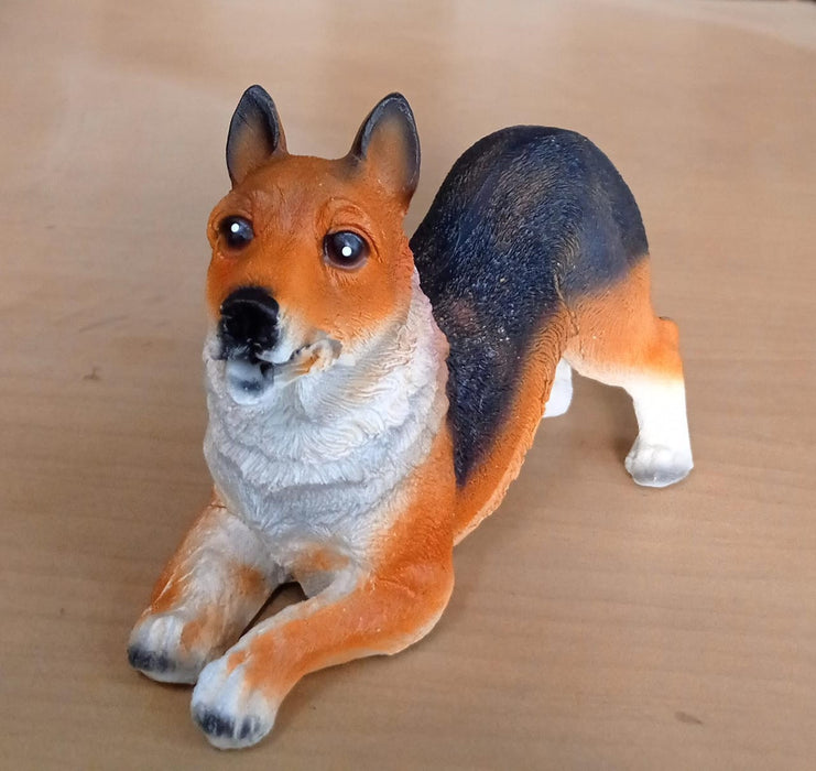 dog toy statue. The toy is orange, black, and white and is lying down on a brown table.