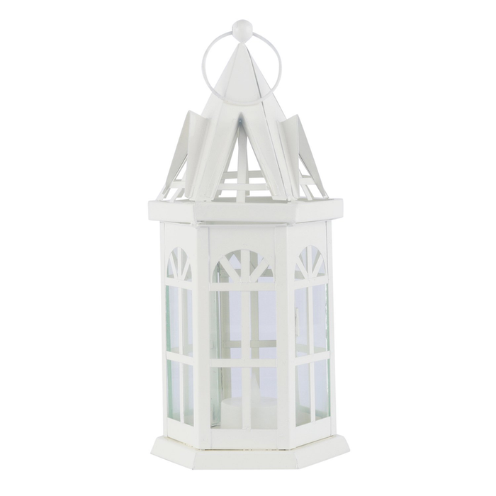 A decorative white metal lantern with a steeple-style roof and glass window panels, containing a small glowing yellow LED candle inside.