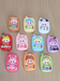 Ten colorful miniature resin toy phone charms arranged on a wooden surface, featuring various pastel and bright colors with cute cartoon character faces.