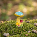 Hand-painted resin mushroom figurine with a blue and yellow cap on a mossy base for fairy gardens and terrariums