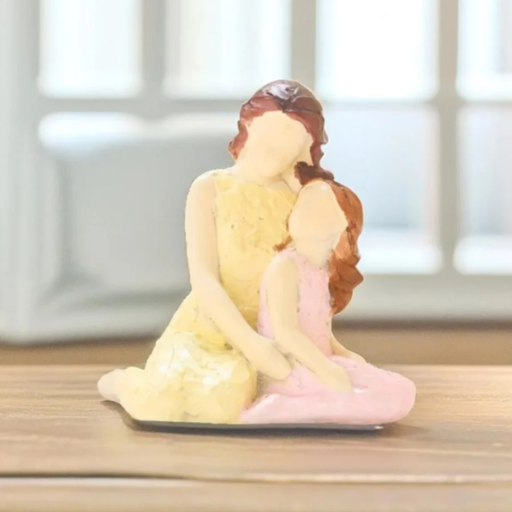 Hand-painted resin figurine of a mother in a yellow dress embracing her daughter in a pink dress, featuring a faceless minimalist design and textured finish.