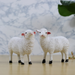 Two cute white sheep figurines with textured wool, pink ears, and black hooves