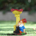 A hand-painted garden gnome figurine relaxing next to a bright yellow and red mushroom bird feeder