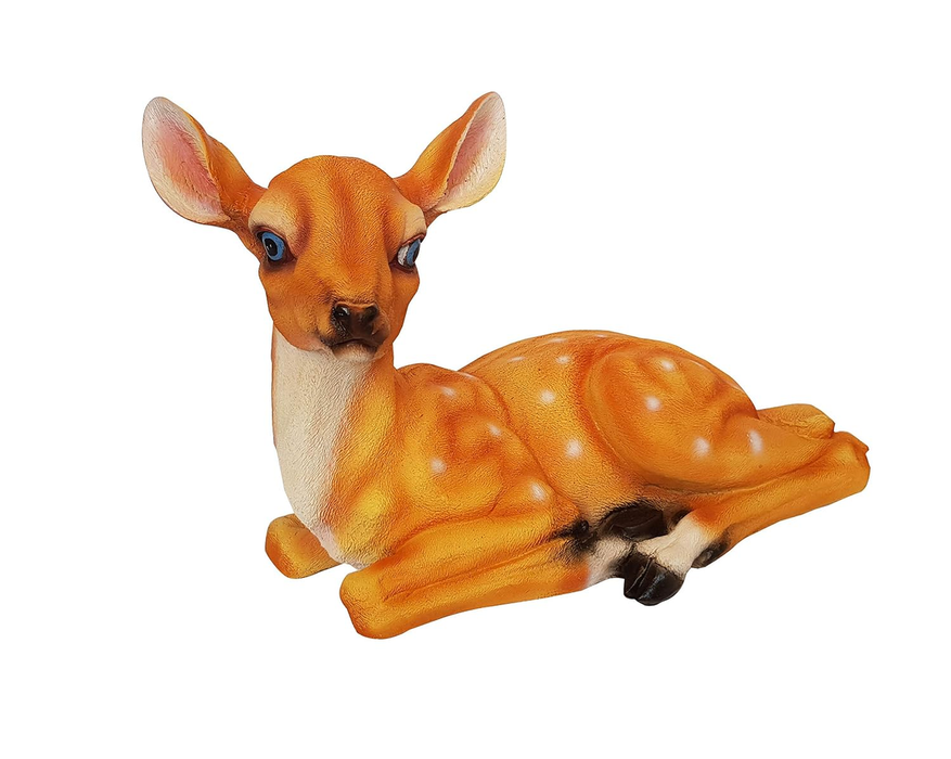 A standard-sized resting deer garden statue with white spots positioned on green grass amongst garden foliage