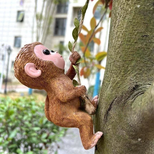 A realistic resin garden statue of a baby monkey with brown fur climbing a decorative vine rope against a tree trunk in an outdoor setting.