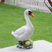 A hand-painted white duck and nest with eggs garden statue standing outdoors on a stone surface with green grass