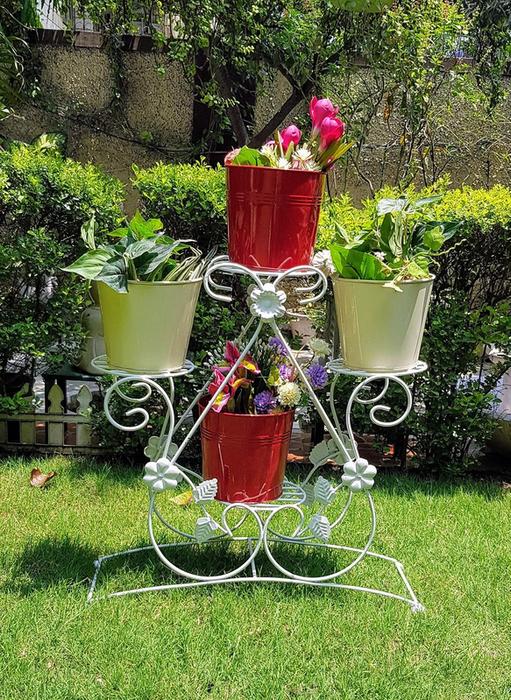 White metal four-tier plant stand featuring decorative floral accents and scrollwork