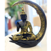Black and gold Buddha statue sitting in a meditative pose on a large hand base, framed by a matching crescent moon arch.
