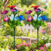 Set of 2 colorful butterfly garden sticks with artificial flowers and green foliage in a garden