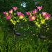 Two solar-powered pink lotus flower garden stakes with glowing yellow firefly lights installed in a green lawn